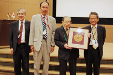 日野原重明氏(聖路加国際病院理事長)へ家紋をデザインした西陣織りが贈られた。左から,杉村和朗氏(神戸大学医学部附属病院長),事務局の渡邉嘉之氏(聖路加国際病院放射線科),日野原氏,齋田大会長。