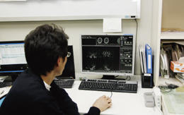 CT室にあるクライアントで画像処理を行う松本部長。ネットワーク型WSはマンパワーの有効活用にもつながると評価する。