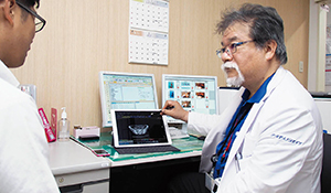 診察室で電子カルテとCSSで診察する松波院長。手前のiPad Proでは仮想化サーバ経由でPACSの画面を表示
