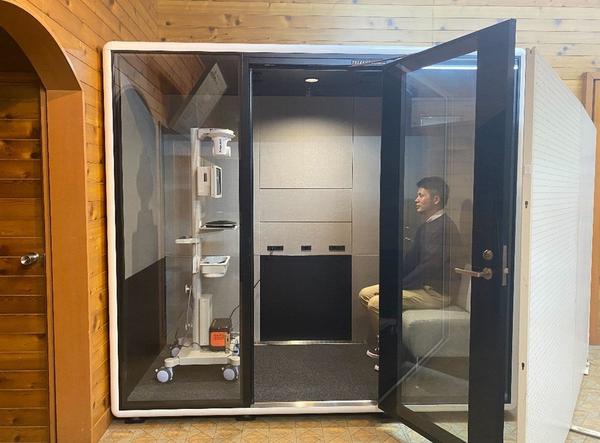 ※「あけのべ憩いの家」に設置した防音個室ブース「TELECUBE」と遠隔医療システム「Doctor Cart」 ※実際は，「TELECUBE」周辺に白いボードを設置し，患者のプライバシーに配慮した形でオンライン診療を行う。