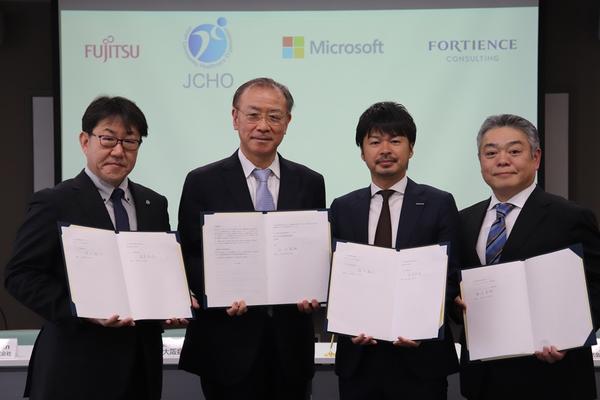 図：調印式に参加した，富士通Japan ヘルスケア事業本部長 桑原裕哉氏（左)，大阪病院 西田 俊朗氏 （左から2番目）と日本マイクロソフト ヘルスケア統括本部　統括本部長　清水 教弘氏（右から2番目），フォーティエンスコンサルティング　ソーシャルバリュークリエイション本部⾧ 重信 卓哉氏（右），（於 大阪病院　2026年2月13日）