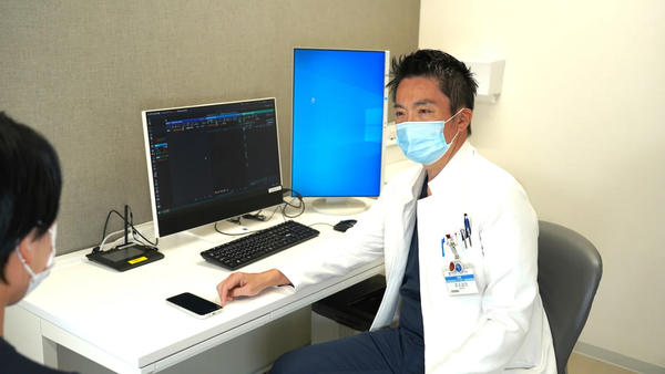 院内専用スマートフォンで「medimo」を使用し，外来診療を行う様子